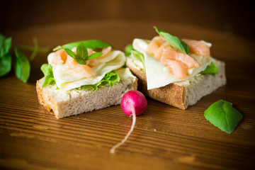 sandwich with cheese, salad leaves and red fish on a wooden
