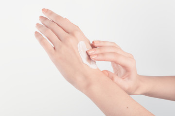 Spa treatment. Close Up of female hands applying hand cream. Woman holding cream tube and applying moisturizer cream on her beautiful hands for clean and soft skin.