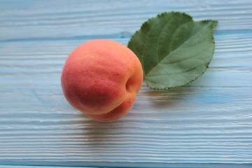 Ripe and sweet peach lies on the blue wooden background.