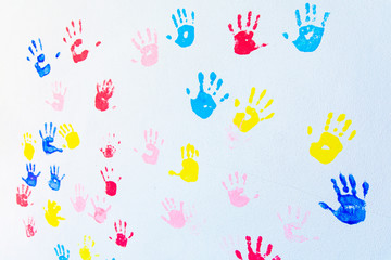 Colorful hand prints of hands isolated on white wall background. Children's handprints on school wall