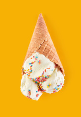 ice cream balls with colored sugar sprinkles in a Waffle Cone on a yellow Background. Vanilla ice cream in a waffle cone.