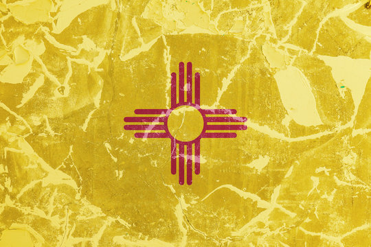 The national flag of the US state New Mexico in against a gray wall with cracks and faults on the day of independence in blue and yellow. Political and religious disputes, customs and delivery.