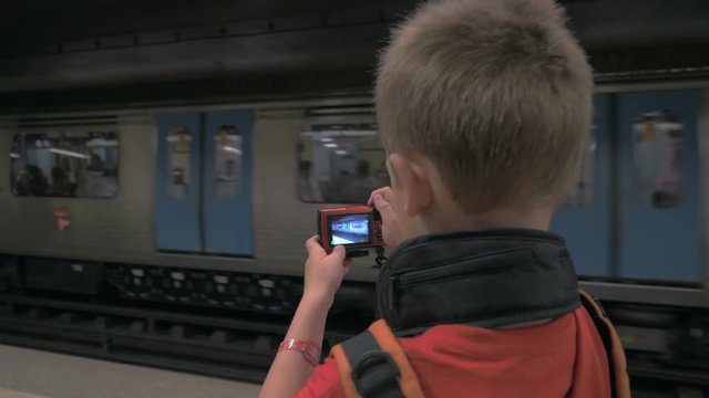 Young photographer taking shots of arriving subway train with his own digital camera