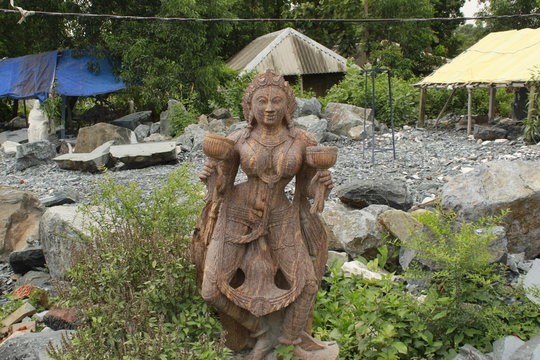 Beautiful/perfect sculpture of Dancing devadasi Holding musical instrument on her hand carved from red sand stone with natural background.An female servant of god or jogini is a girl.
