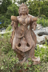 Fototapeta na wymiar Beautiful/perfect sculpture of Dancing devadasi Holding musical instrument on her hand carved from red sand stone with natural background.An female servant of god or jogini is a girl.