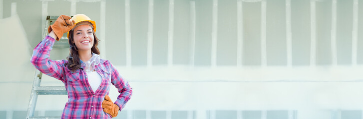 Female Contractor Wearing Hard Hat Against Dywall Banner Background with Ladder