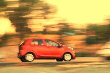 Fototapeta na wymiar Red car moving fast along the road