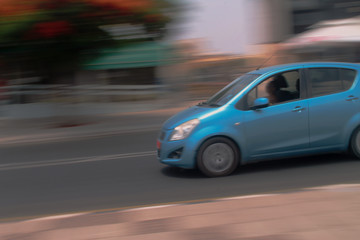 Fototapeta na wymiar Blue car moving fast along the street