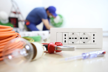 electrician work with electrical equipment in the foreground, bulb, tools and socket, electric...