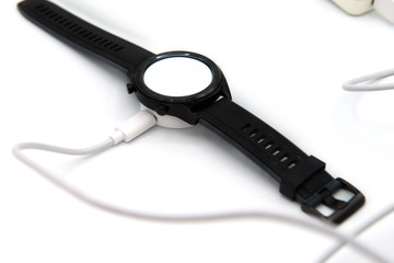 Watch and battery charger separately on white background 