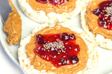 crunchy natural peanut butter strawberry jam jelly sandwich with chia seeds on rice cake bread. Proper nutrition diet vegetarian breakfast on plate next to knife with peanut butter