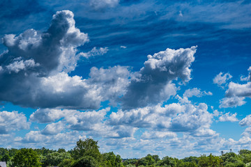 White clouds in the blue sky over the forest.