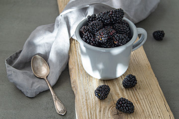 Fototapeta na wymiar Ripe blackberries in a bowl on a wooden Board on a dark background. Scandinavian style.