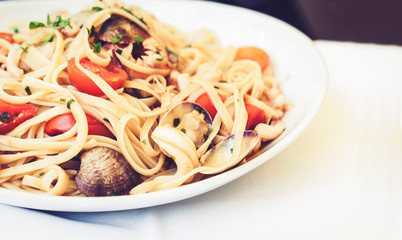 Seafood pasta spaghetti linguine wish mussels, clams, cherry tomatoes, fresh parmesan on the white plate in restaurant in Catania, Sicily, Italy.