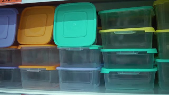 Point of view on shelf with colorful reusable food containers in supermarket.Camera moves along the rack with lunch boxes, close-up.