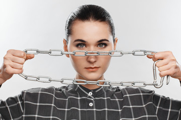 Portrait of a girl in a gray plaid shirt, with a chain in her hands and with picked up hair