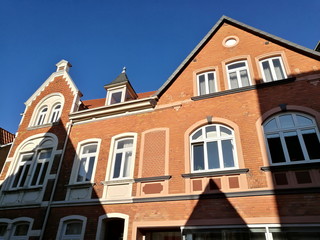 Altbau mit Spitzgiebel und schöner rotbrauner Klinkerfassade vor blauem Himmel im Sonnenschein in...