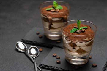 Classic tiramisu dessert in a glass on stone serving board on dark concrete background