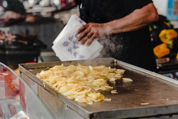 street food - grilled onions mixed with male hands