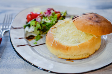Julienne in a bun with healthy salad decorated balsamic sauce. Edible plate made of bread.