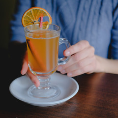 Female hands holding a glass of sbiten, traditional russian winter drink made of honey and spices.