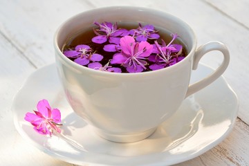 White cup with a tea from the flowers of fireweed  on white background closeup