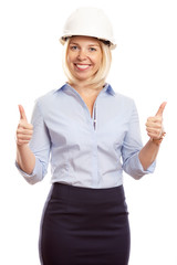 Smiling young woman in office clothes and a construction helmet on her head. Thumbs up. Vertical. White background.