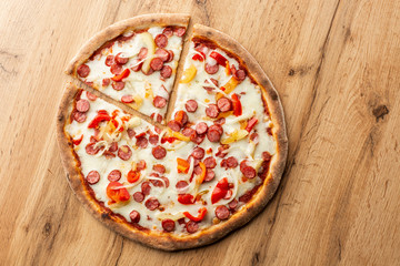 Top view of hot pizza with chili pepper , hot sausages, onion, tomatoes and cheese.
