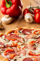 Top view of delicious Capricciosa Pizza on wooden table. Ingredients peeled tomato, cheese, ham, mushrooms, salami.