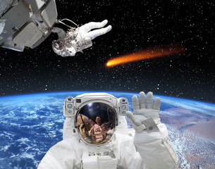 Obraz na płótnie Canvas Astronaut waving in front. Comet on the background. The elements of this image furnished by NASA.