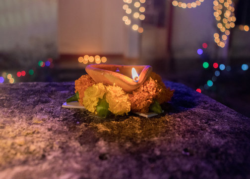 Mud lamp with yellow, bright flame, a symbol of festivity and hope. The lamp is supported by marigold flower. The picture was captured during the festival of Deepawali, India