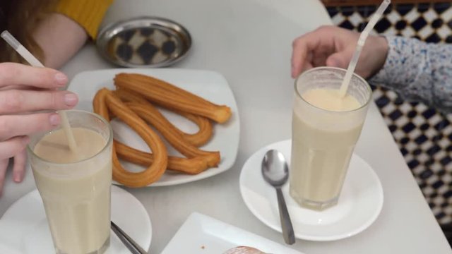 Man and woman eating in cafe of Valencia. Traditional horchata with fartons and churros