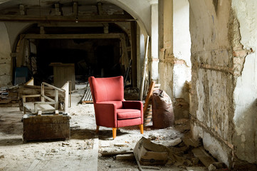 red comfort chair in a destroyed house full of demolition waste