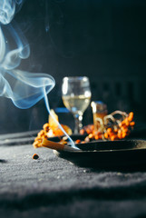 cigarette smoke in an ashtray on the background of a glass with alcohol. Black background