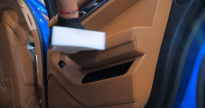 A woman at a car wash does a full dry-cleaning of all parts of a car using special chemistry, cloths, sponges and brushes. Concept of: Full car cleaning, Dry cleaning, Professional service. Car, Work.