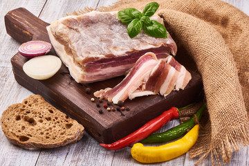 Homemade Chunks of salted bacon on a cutting rustic board