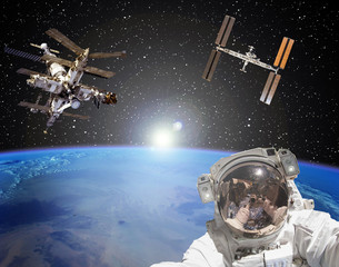 Astronaut, space stations and sunrise on the backdrop. The elements of this image furnished by NASA.