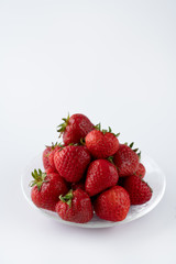 Freshly picked organic strawberries in a glass bowl. White background, water, isolated, high resolution