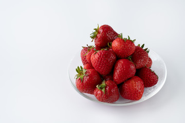 Freshly picked organic strawberries in a glass bowl. White background, water, isolated, high resolution