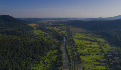 Naklejka premium Aerial view of the Carpathian mountains. Natural background with geometric pattern - beige and red rectangles of the fields and roofs and lines of roads and trees. Zakarpattia, Ukraine.