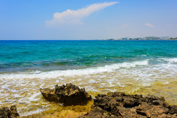  black and yellow rocks and stones and blue sea on the shore of Ayia Napa, Cyprus