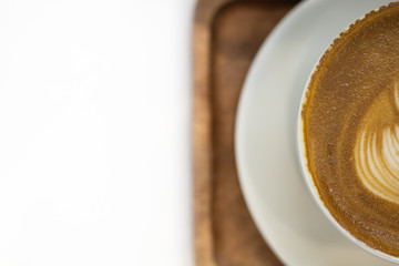 Close up top view of haft white cup of hot coffee latte with texture of milk form art and plate on wooden tray with copy space for text.