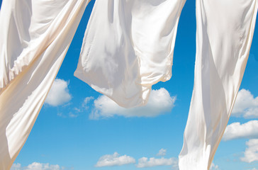 the wind blows white awnings, on the seashore against the blue sky