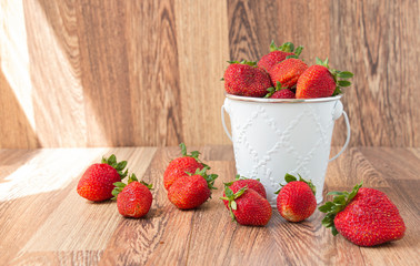Fresh ripe organic red sweet strawberries in a white bucket and on a wooden table