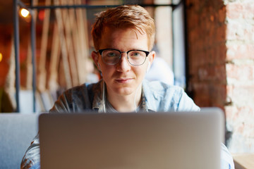 Young man works on the laptop in the cafe.