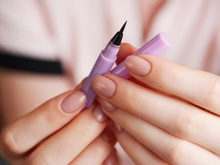 Woman's beauty blogger hands holding sample liner pencil box professional hi-end cosmetics with...