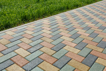 Colorful cobblestone road pavement and lawn divided by a concrete curb.