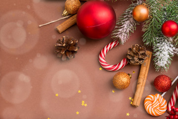 fir branch, fir cones, gold and red Christmas balls, Lollipop on a brown background, cinnamon sticks, stars