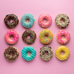 Colorful sweet background. Delicious glazed donuts on pink background. 