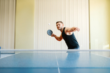 Man with racket and ball playing ping pong indoors